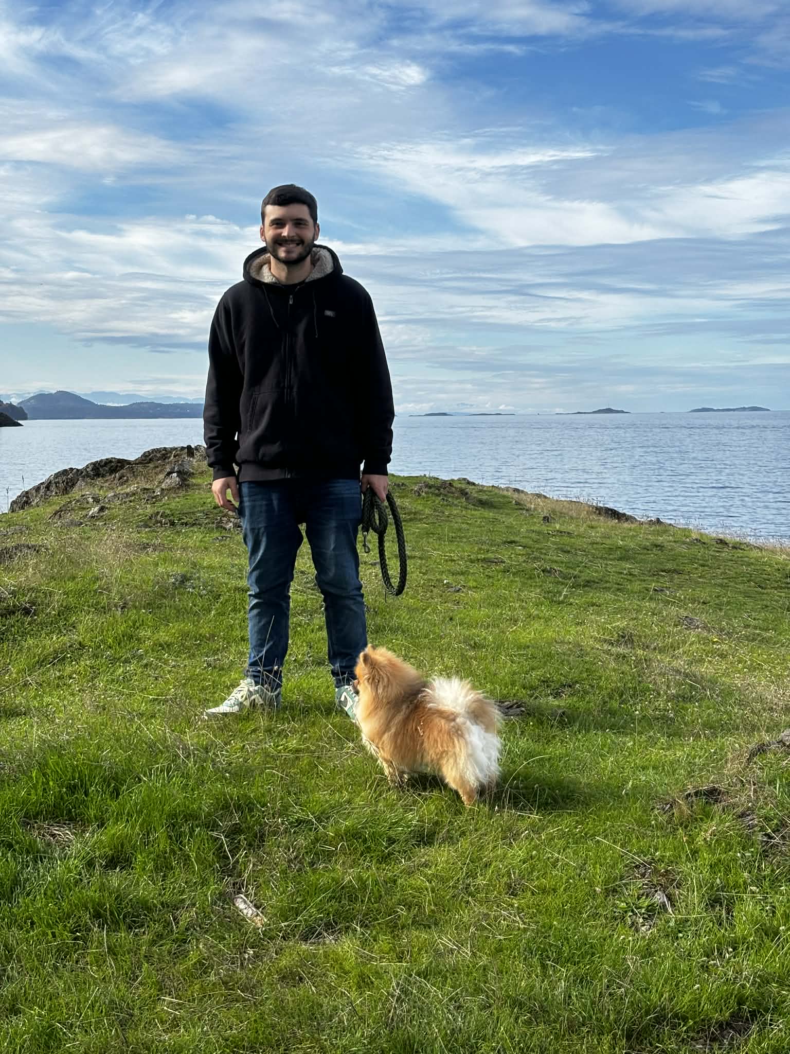 Kim Weber standing on a coastal cliff with his Pomeranian